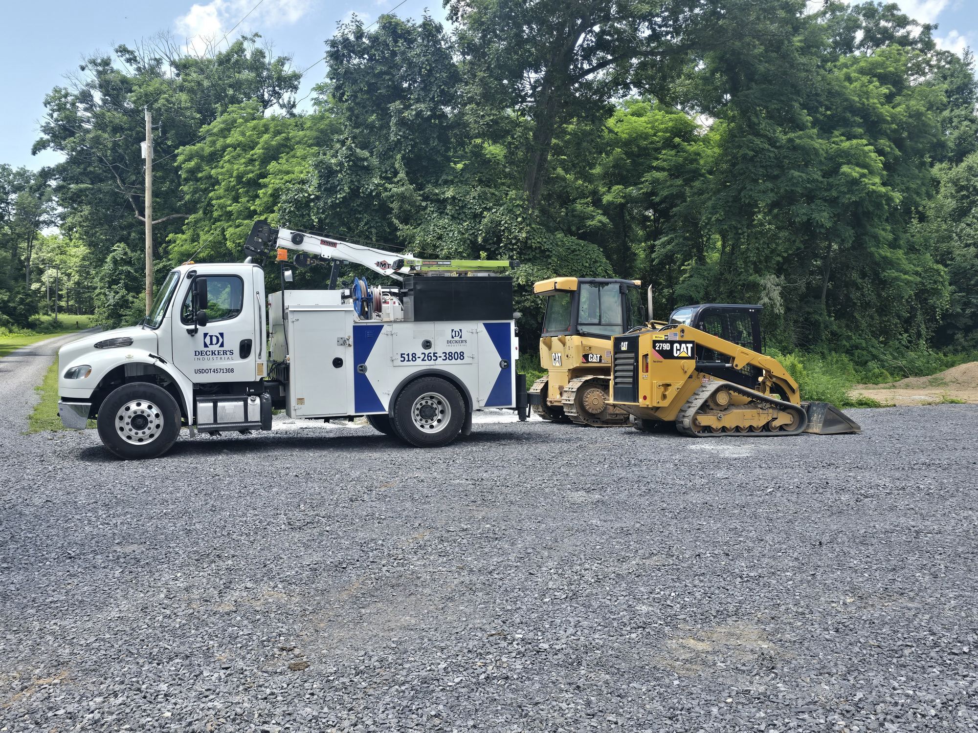 Decker's Industrial service truck with boom crane parked beside a compact track loader and a dozer at a Capital Region job site