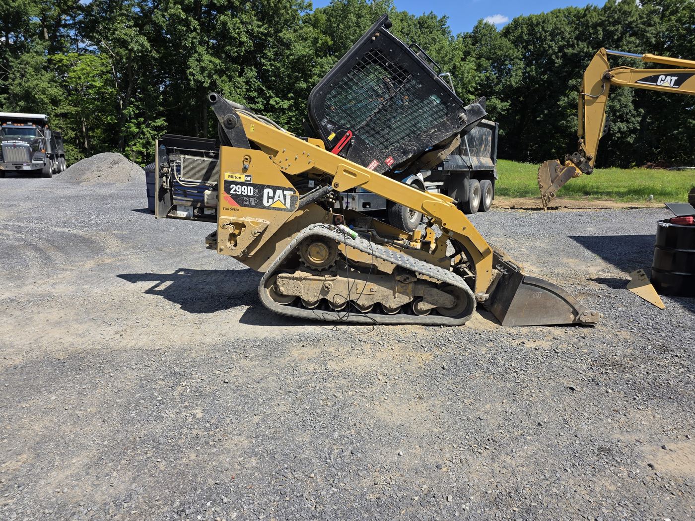 Compact track loader with the rear hood raised beside the Decker's Industrial service truck
