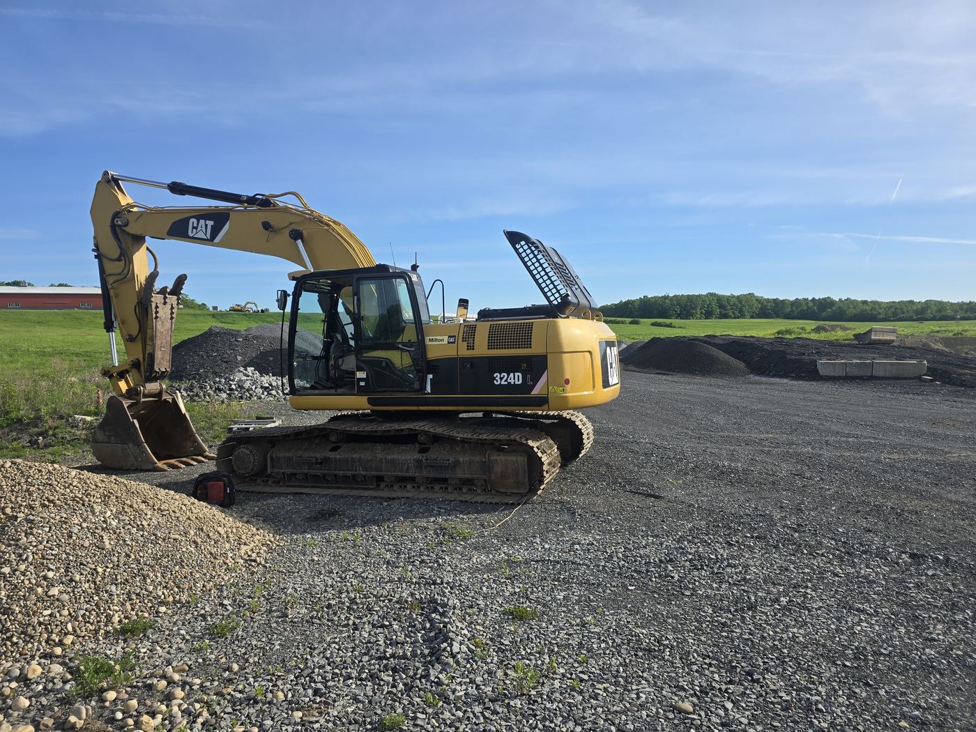 Excavator parked on a gravel pad after field service in the Capital Region
